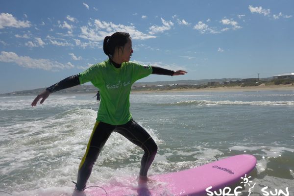standing up in  a surf board during a surf lesson